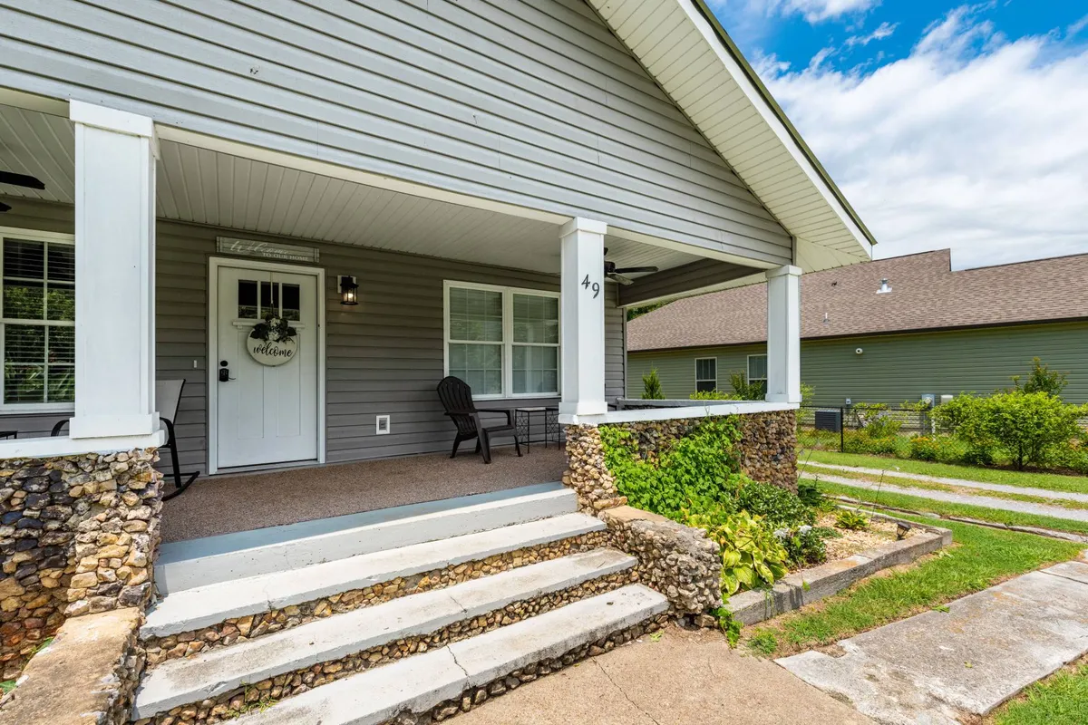 A close-up view of the front door, complemented by a sturdy rock wall and comfortable porch seating. The scene exudes a welcoming, homey feel, inviting guests (and their furry companions) to relax outdoors.