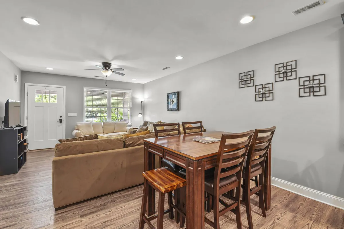 A welcoming interior with a sofa, a dining table set for six, and a front door accented with decorative wall art. The layout highlights the seamless transition from the living area to the dining space, ideal for shared meals, planning adventures, or simply unwinding together.
