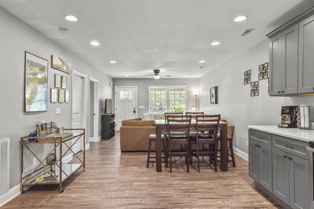 A spacious, inviting interior with a dining table set for a meal, a cozy sofa, and tasteful kitchen cabinetry. The arrangement suggests a welcoming space for group gatherings, shared meals, and conversation.
