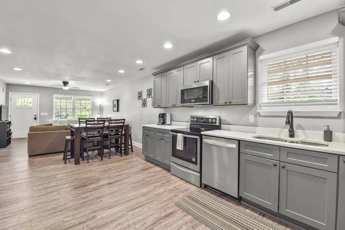 A bright, open-plan living space integrates a kitchen island, dining table, and cozy living area. The scene is welcoming and designed for togetherness, suggesting a comfortable space for cooking, dining, and movie nights after a day of exploring.